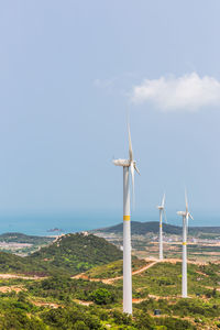 Windmills on sea against sky