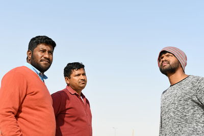 Three friends standing outdoors against sky