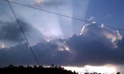 Low angle view of electricity pylon against cloudy sky