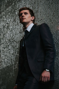 Portrait of young man standing against wall