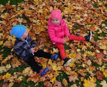 Girl and boy sitting on autumn leaves