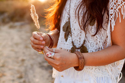 Woman in boho style holds a spikelet at sunset