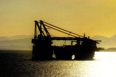 Silhouette of cranes at harbor during sunset