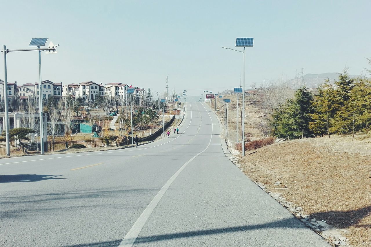 clear sky, transportation, road, the way forward, street, street light, mode of transport, land vehicle, car, blue, road marking, copy space, sunlight, building exterior, diminishing perspective, incidental people, built structure, sky, tree, city