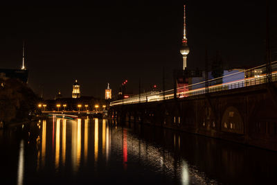 Illuminated bridge over river at night