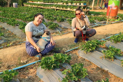 Portrait of friends sitting at vegetable garden