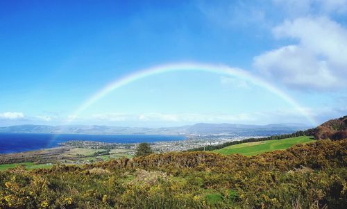 Scenic view of rainbow over landscape against sky