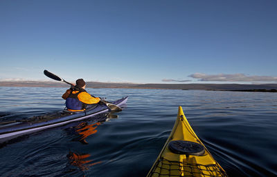 Two sea kayaks navigating through still lake on the icelandic highland