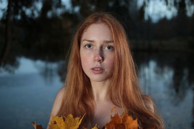 Portrait of beautiful young woman against lake