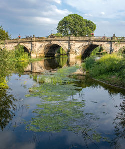 Arch bridge over river against sky