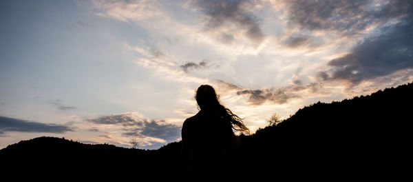 Silhouette woman standing against sky during sunset