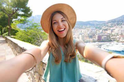 Attractive tourist girl takes selfie picture with monte-carlo cityscape, monaco