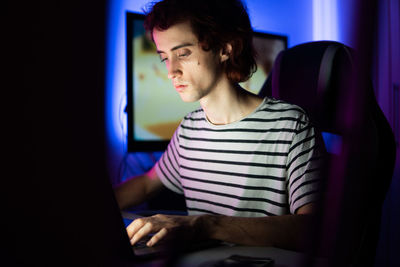 Man using laptop while sitting in darkroom