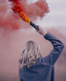 Rear view of woman with arms raised against sky