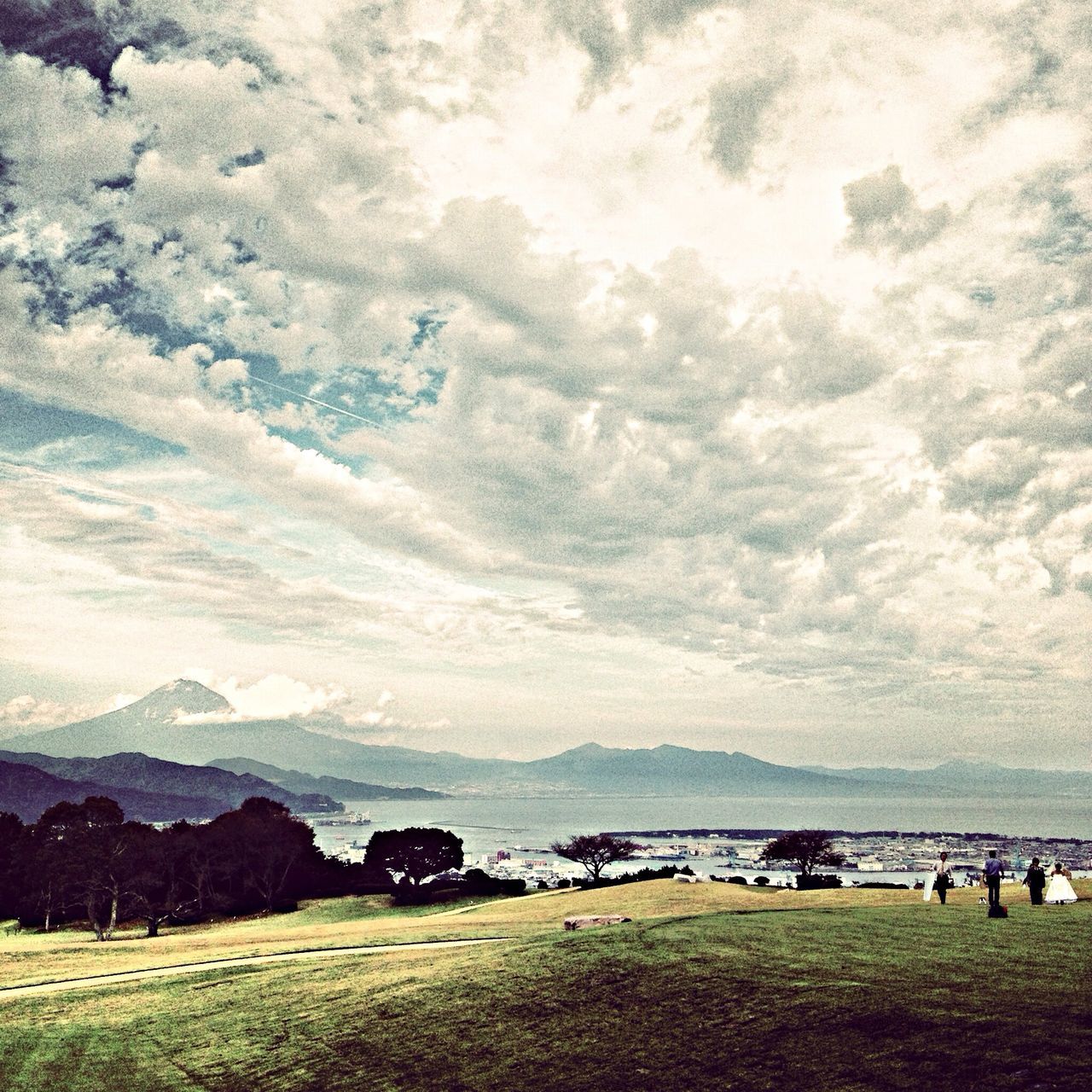 sky, water, cloud - sky, scenics, grass, tranquil scene, beauty in nature, tranquility, nature, sea, cloudy, landscape, mountain, cloud, leisure activity, incidental people, day, field, lifestyles