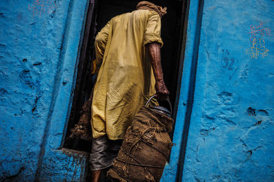 Rear view of man standing against blue wall