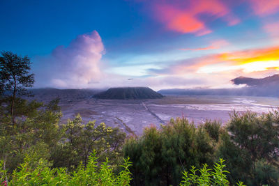 Scenic view of landscape against dramatic sky during sunset