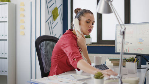 Businesswoman talking on landline phone in office