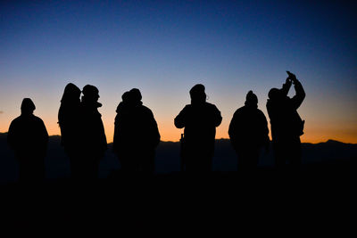 Silhouette people standing against clear sky during sunset