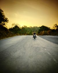 Man riding motorcycle on road against sky