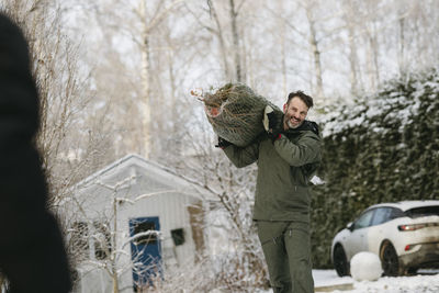 Man carrying christmas tree at winter