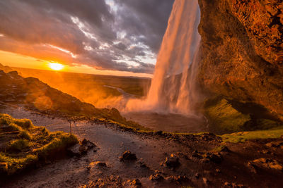 Scenic view of waterfall against sky during sunset