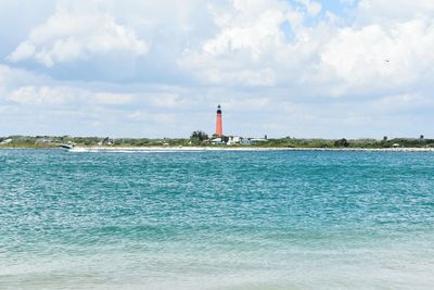 Lighthouse by sea against sky