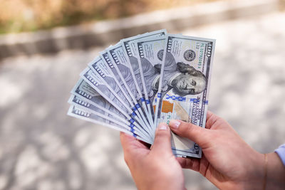 Cropped hand of man holding banknotes outdoors