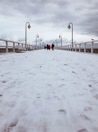 Snow covered walkway against sky during sunset