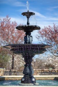 Statue by fountain against sky