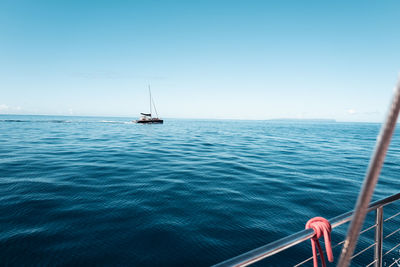 Sailboat sailing on sea against clear blue sky