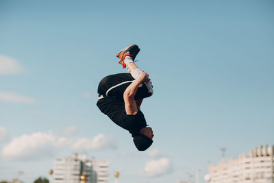 Low angle view of man jumping against sky