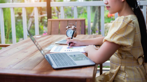 Side view of woman using mobile phone on table