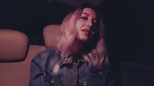 Low angle portrait of young woman sitting in car