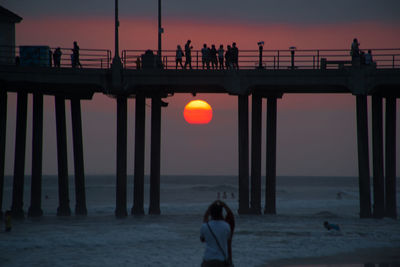 Silhouette of woman standing at beach during sunset