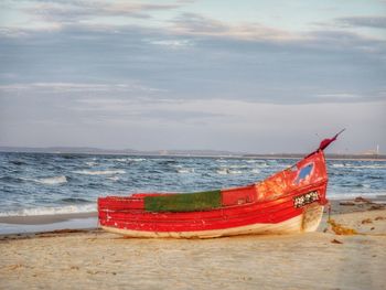 Boat moored on beach against sky