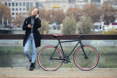 Full length of man standing on bicycle in city