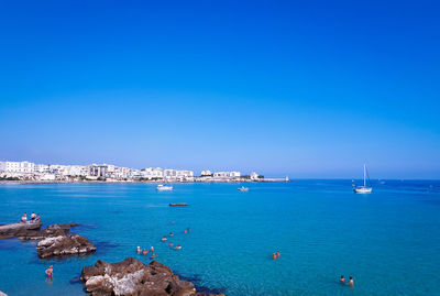 Sailboats in sea against clear blue sky