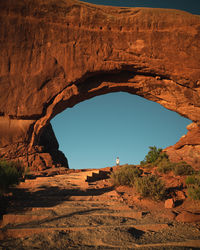 Distant view of man standing by rock formation