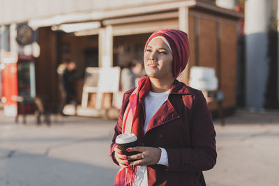 Portrait of young woman standing in city