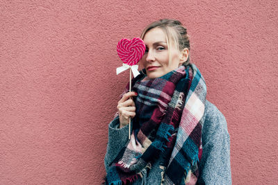 Portrait of a young woman holding red wall