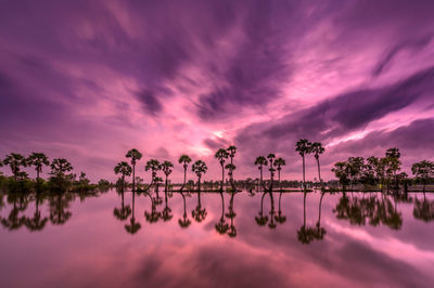 Scenic view of lake against dramatic sky during sunset