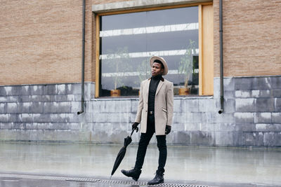 Full length portrait of man standing against building