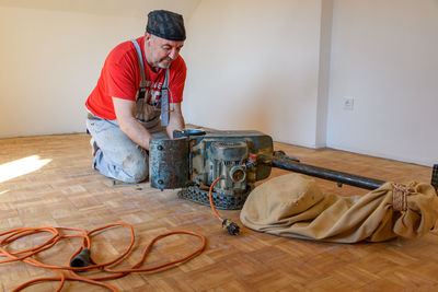 Man sanding hardwood floor with grinding machine