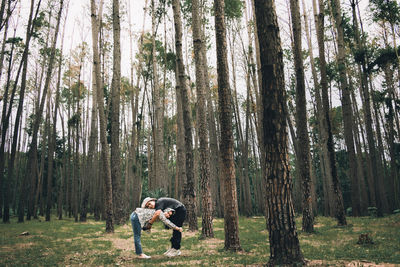 Side view of man standing amidst trees in forest