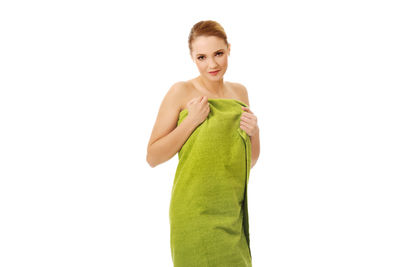 Portrait of young woman wrapped in green towel while standing against white background