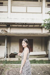 Portrait of woman standing by house