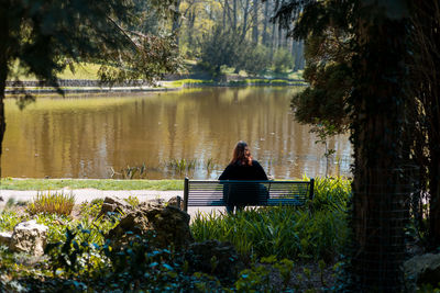 Rear view of woman sitting by lake