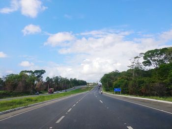 Road by trees against sky