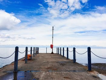 Wooden pier on sea against sky